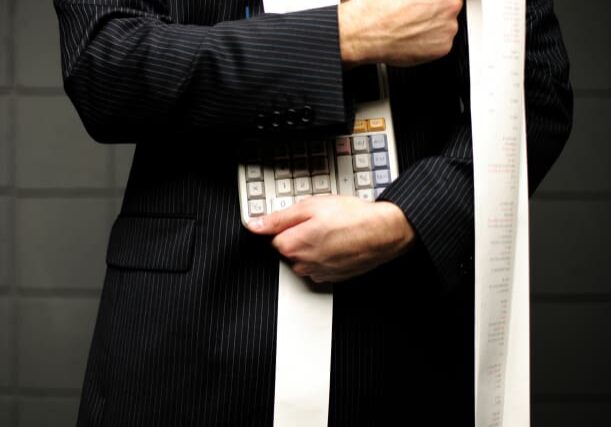 Businessman holding calculator and receipt.